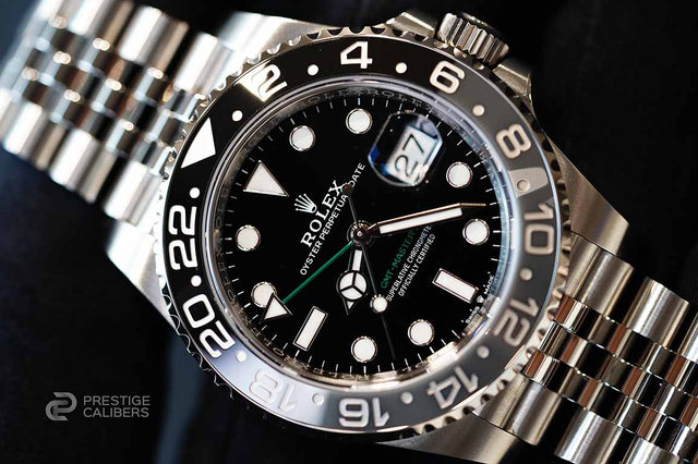 Close-up of a Rolex watch with a black dial and silver metal band.