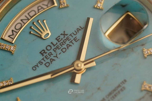 Close-up of a Rolex watch face with turquoise dial and gold accents.